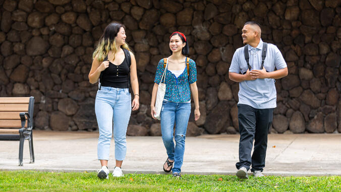 Three smiling students walking