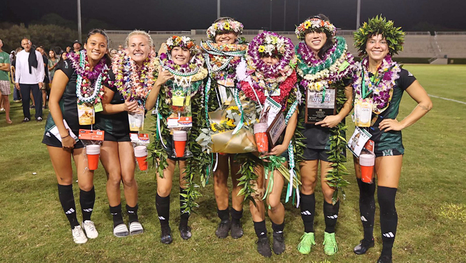 people in uniforms wearing lei standing and smiling