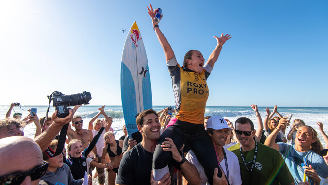 woman on peopleʻs shoulders holding up her hands