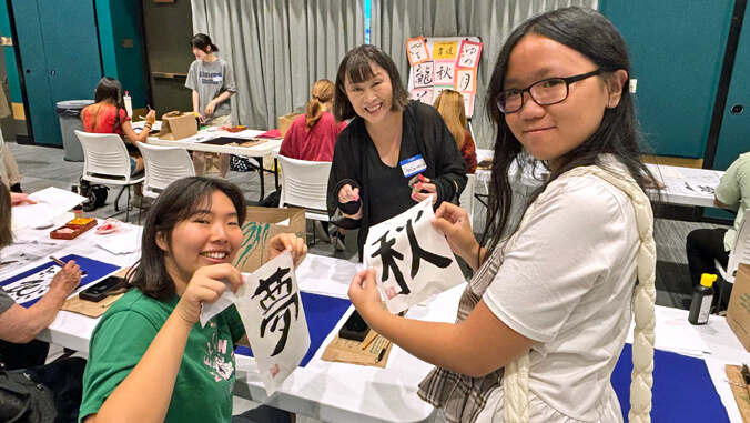 2 students holding up Japanese calligraphy