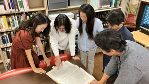 people looking at a textbook on a desk