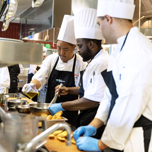 3 chefs in a kitchen preparing food