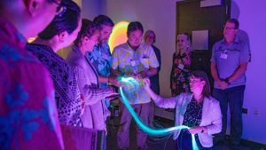 people looking at person holding glowing blue strands