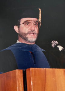 Marsella in cap and gown speaking at a podium