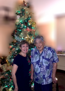 two people standing in front of a Christmas tree