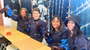 4 people in front of indigo dyed cloth