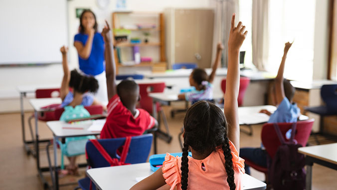 Children raising hands in a classroom