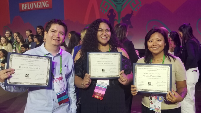 Three people holding certificates