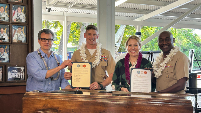 four people pose during a signing ceremony