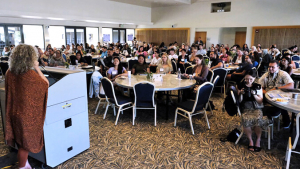 large room filled with people watching a speaker