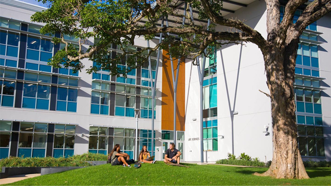 student sitting on grass in front of a building