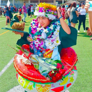 Abe wearing graduation gown, lei, holding flowers