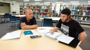 2 student sitting at a table in the library