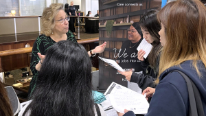 woman talking to students at career fair booth