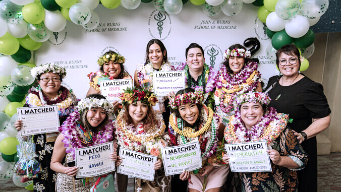 Group of people wearing lei, holding signs