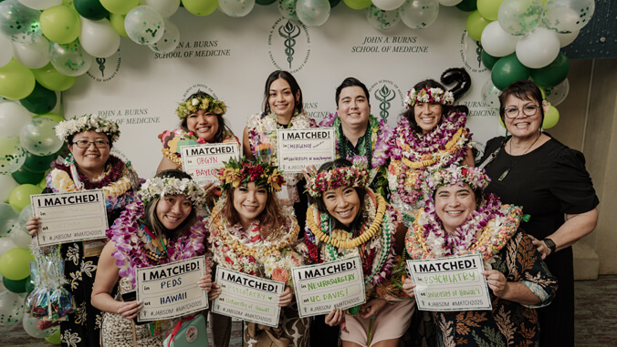 Group of people wearing lei, holding signs