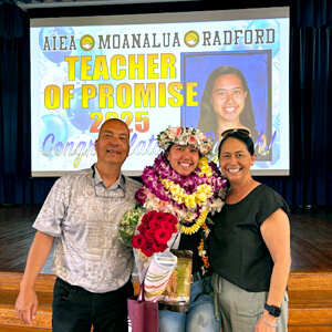 3 people in front of a Teacher of Promise screen